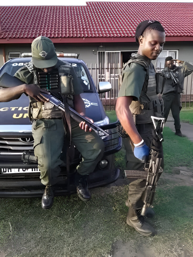 2 security men fully armed in front of a car